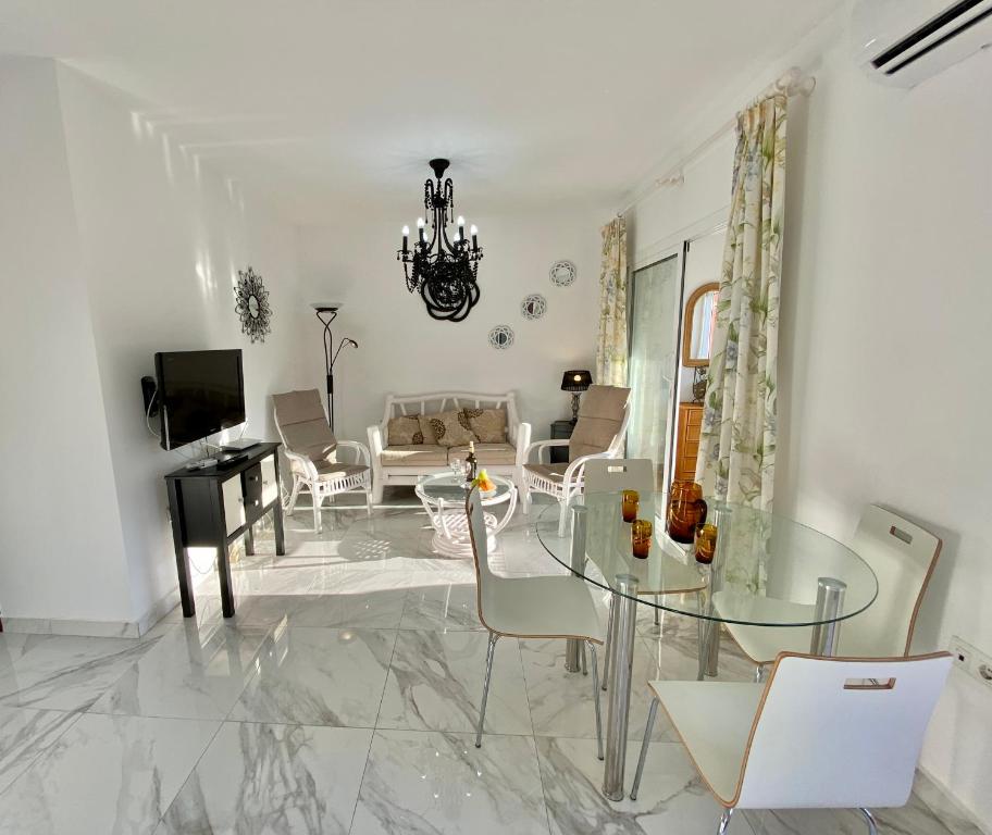 内尔哈SHR043 Nerja Medina Apartamento cerca de Playa Torrecilla的客厅配有玻璃桌和椅子