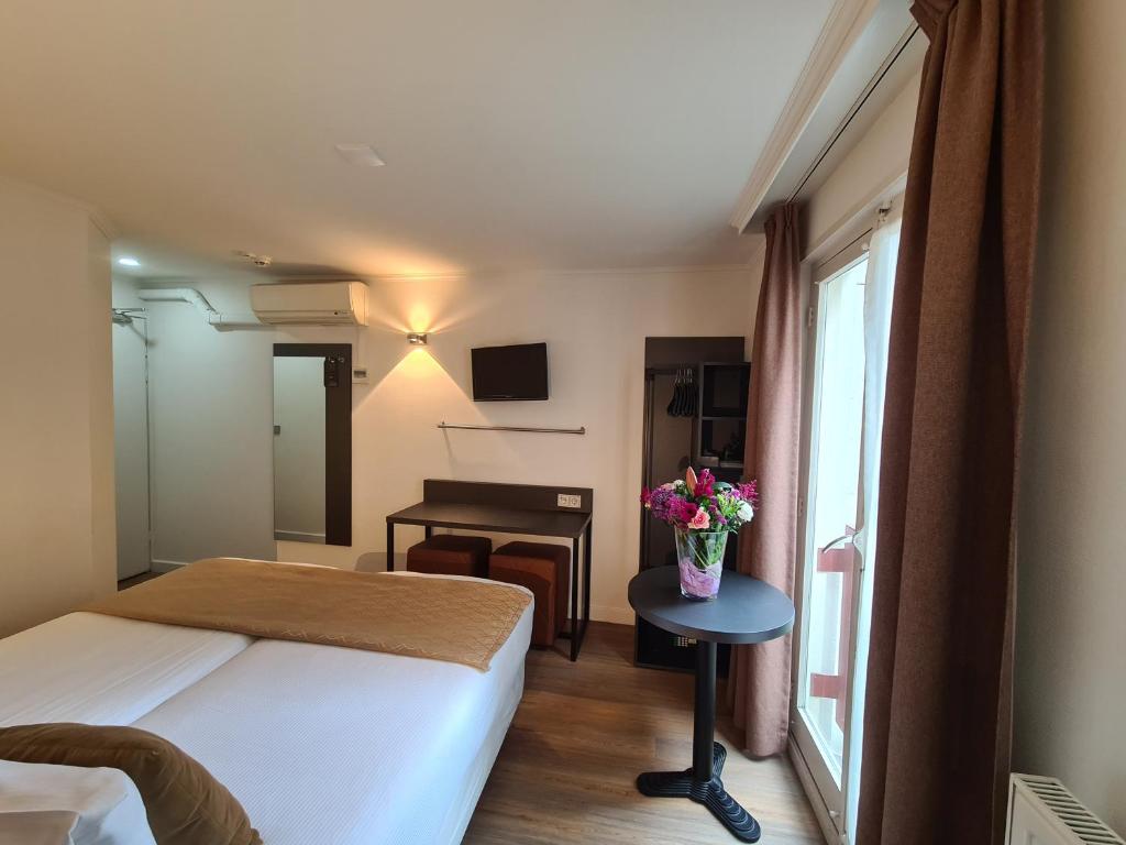 阿姆斯特丹大道酒店的配有床和鲜花桌的酒店客房