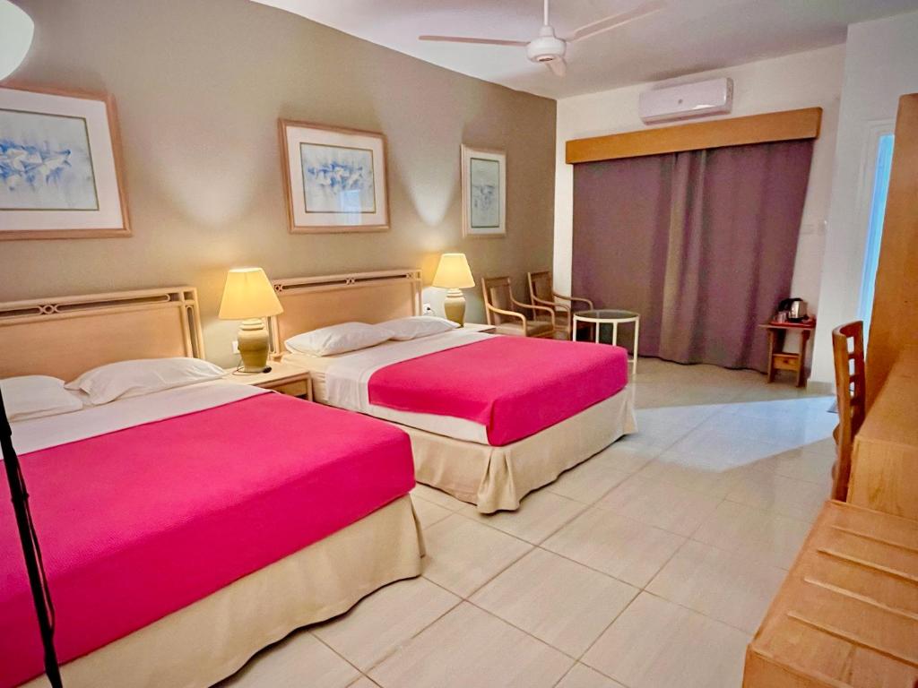 赫尔格达Masaya Hurghada Rooms的酒店客房,配有两张带粉红色床单的床