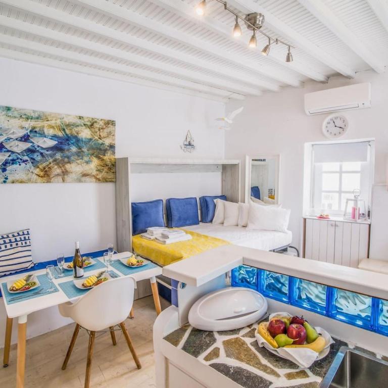 米克诺斯城Like a white seagull in Mykonos!的一间房间,配有一张床和一张桌子,上面有水果