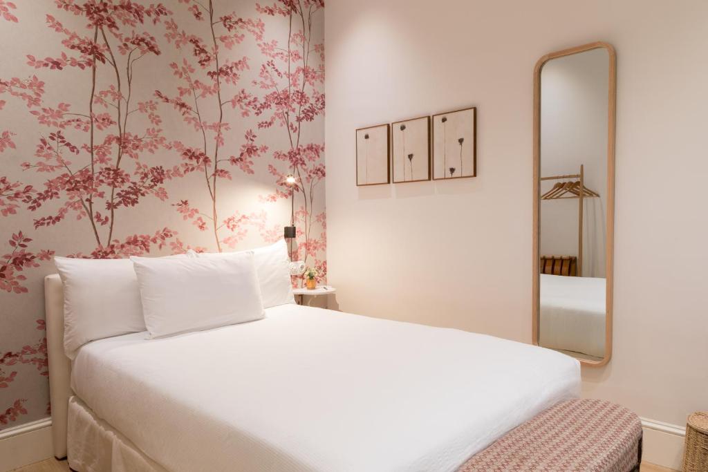 塞维利亚Hotel Tayko Sevilla的卧室配有白色的床和镜子