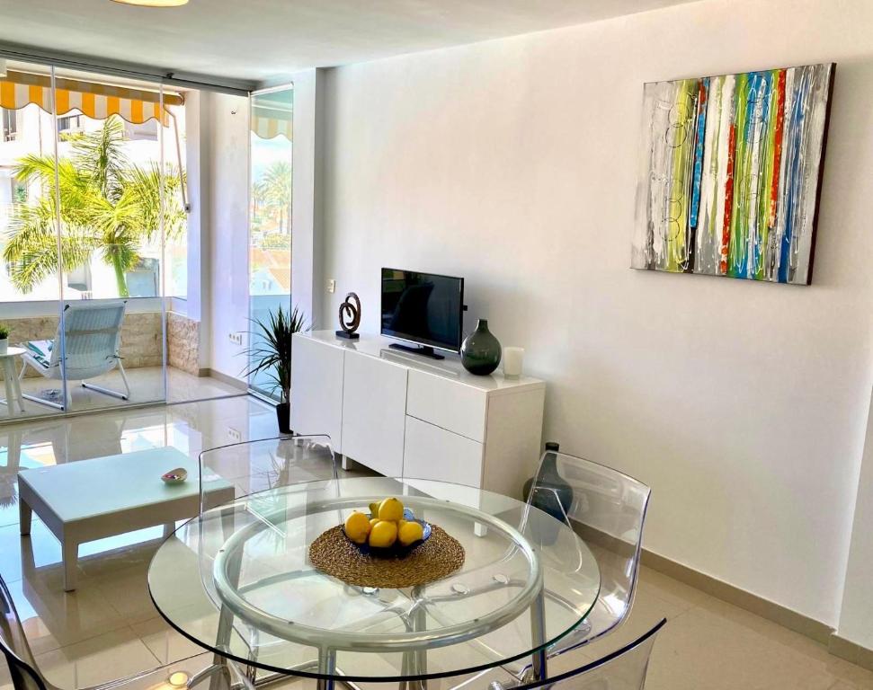英格兰海滩Tanife 310 - Playa del Ingles comfort Suite with Sunset view的客厅配有玻璃桌和电视