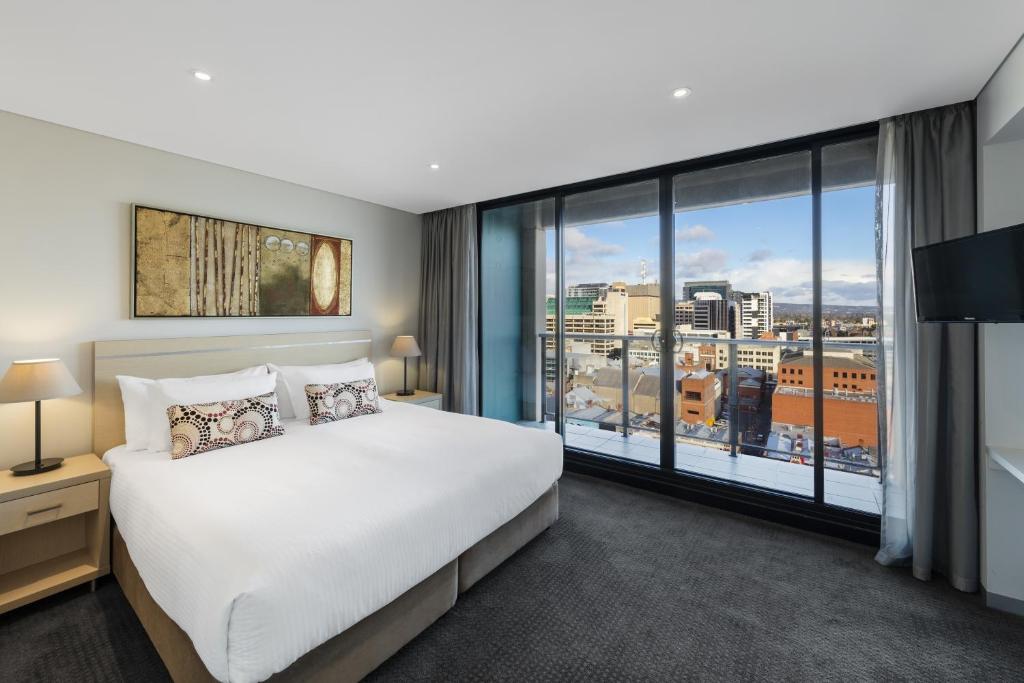 阿德莱德Oaks Adelaide Horizons Suites的一间卧室设有一张大床和一个大窗户