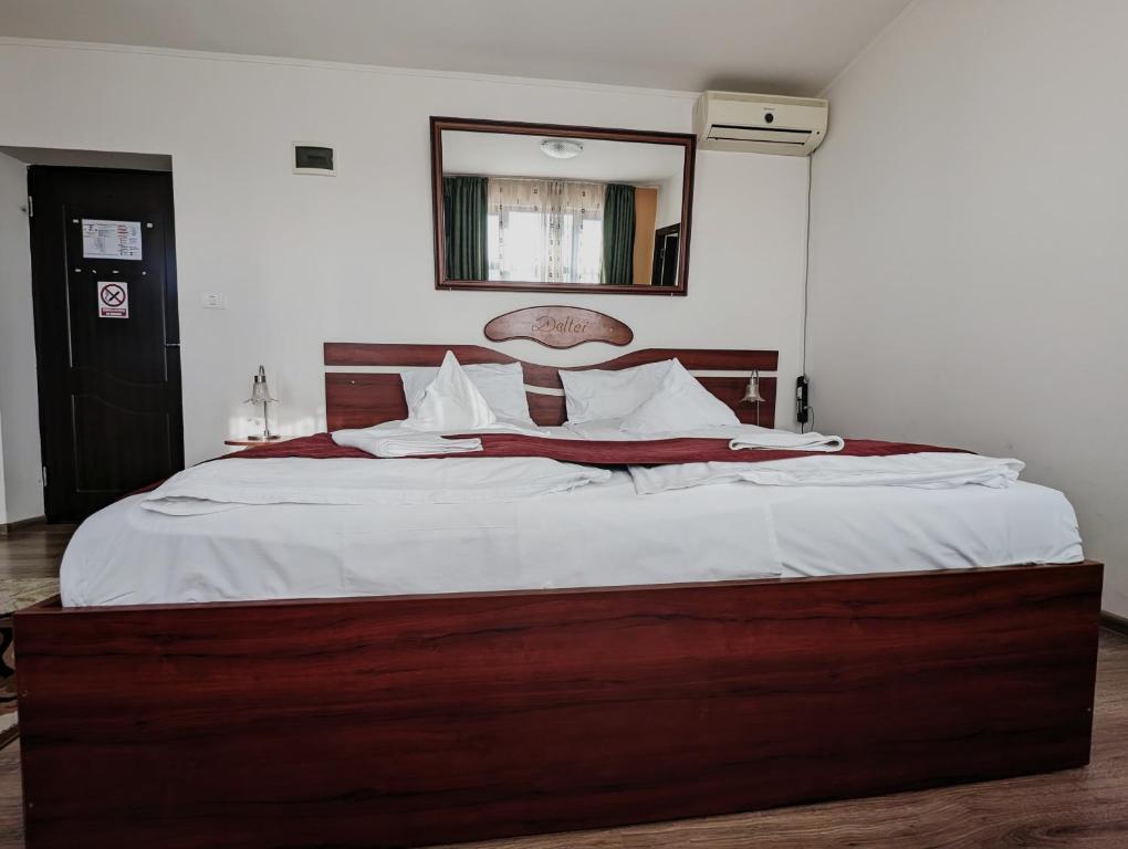 ŞaguConacul de pe Lac的一间卧室配有一张带白色床单和镜子的大床