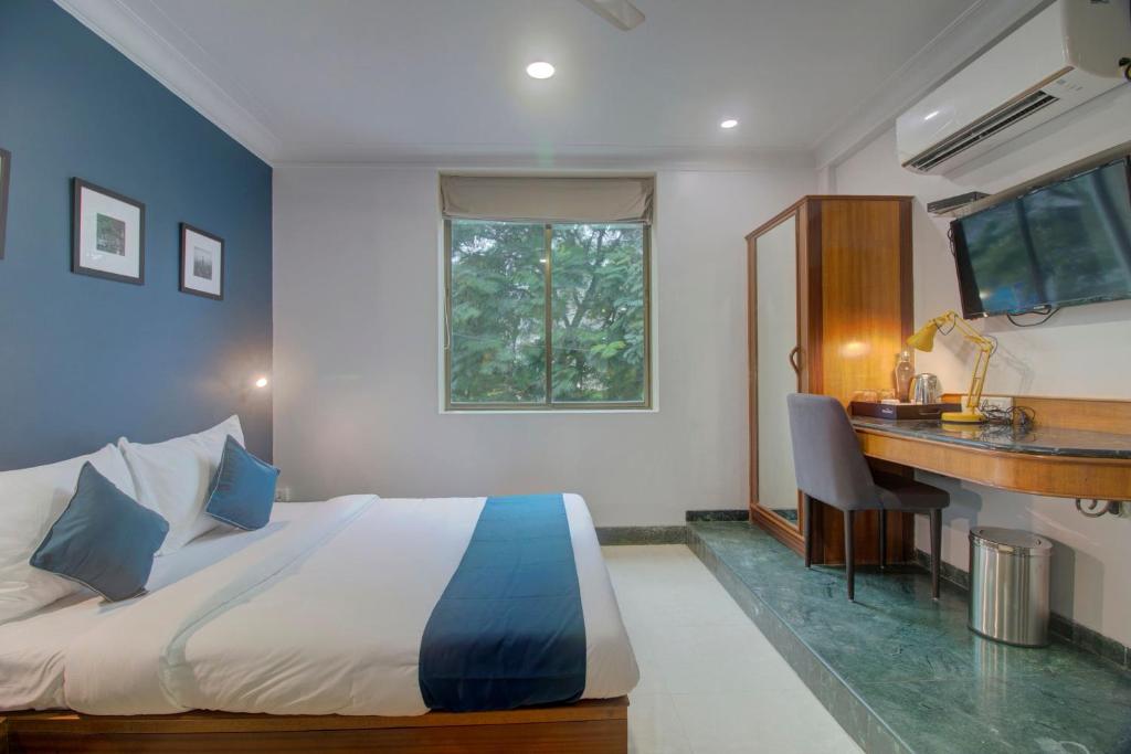 孟买OYO SilverKey Hotel Manas Residency的一间卧室配有一张床、一张书桌和一个窗户。