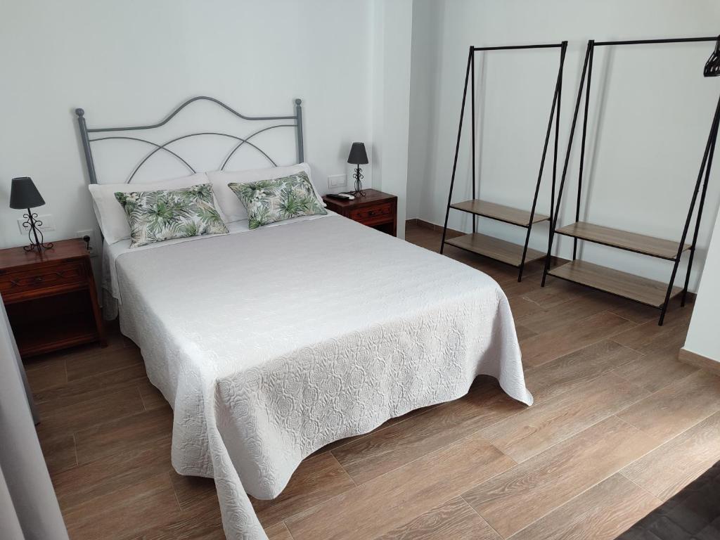 卡莫纳Casa dúplex en el centro的一间卧室配有一张带2个床头柜的大型白色床
