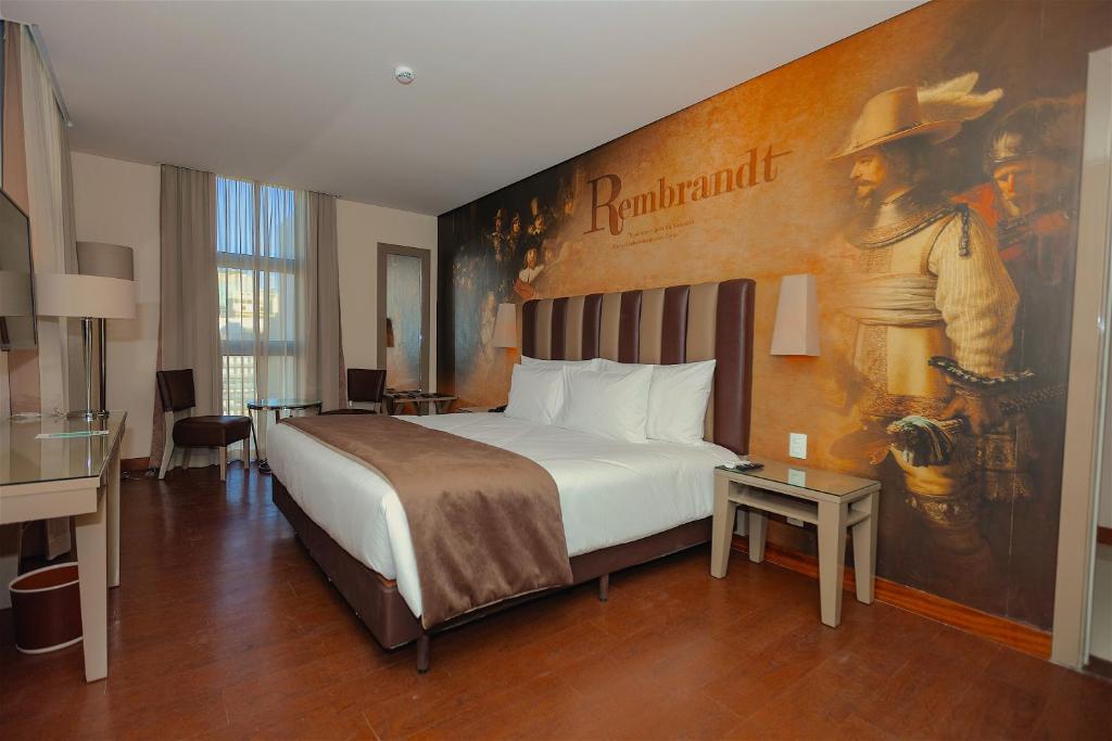 圣保罗Vila Galé Paulista的酒店客房的墙上设有一张带绘画的床铺。