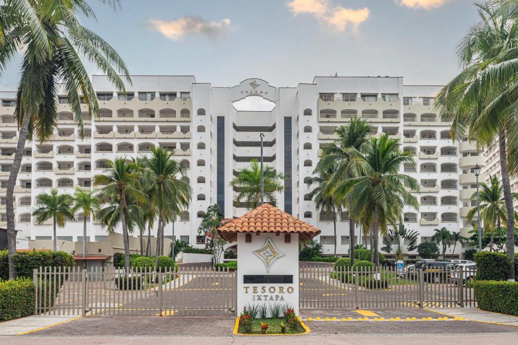 伊斯塔帕Tesoro Ixtapa Beach Resort的一座白色的大建筑,前面有棕榈树