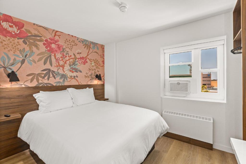 圣地亚哥Uptown Inn by Vantaggio Suites的卧室配有白色的床和窗户。