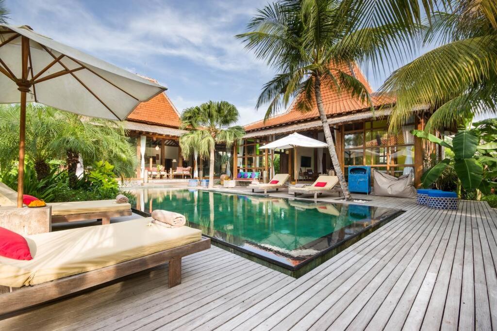 坎古Villa Desa Roro的一个带床和遮阳伞的度假游泳池