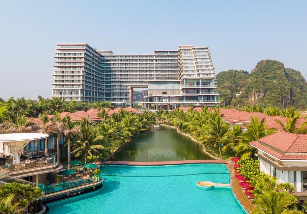 岘港KOI Resort & Residence Da Nang的一座带游泳池、棕榈树和建筑的度假村