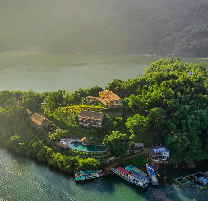 枚州县Mai Chau Hideaway Lake Resort的水中拥有房屋和船只的岛屿