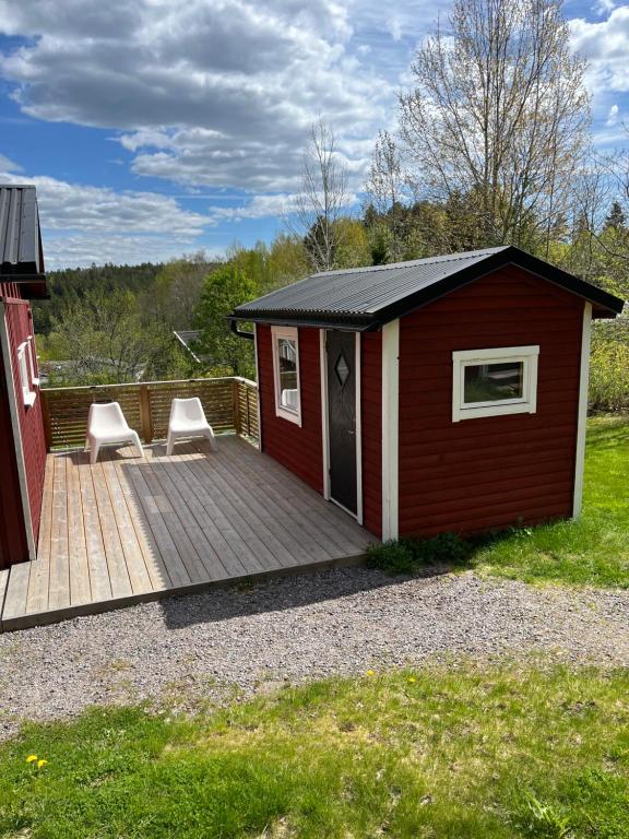 ÅbyRenoverat boende med närhet till Kolmårdens djurpark的木制甲板上带两把椅子的红色棚子