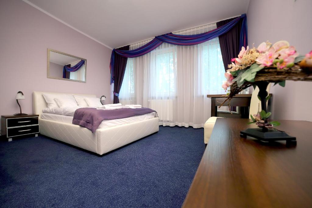 MońkiZajazd Monki的一间卧室配有一张床和一张鲜花桌