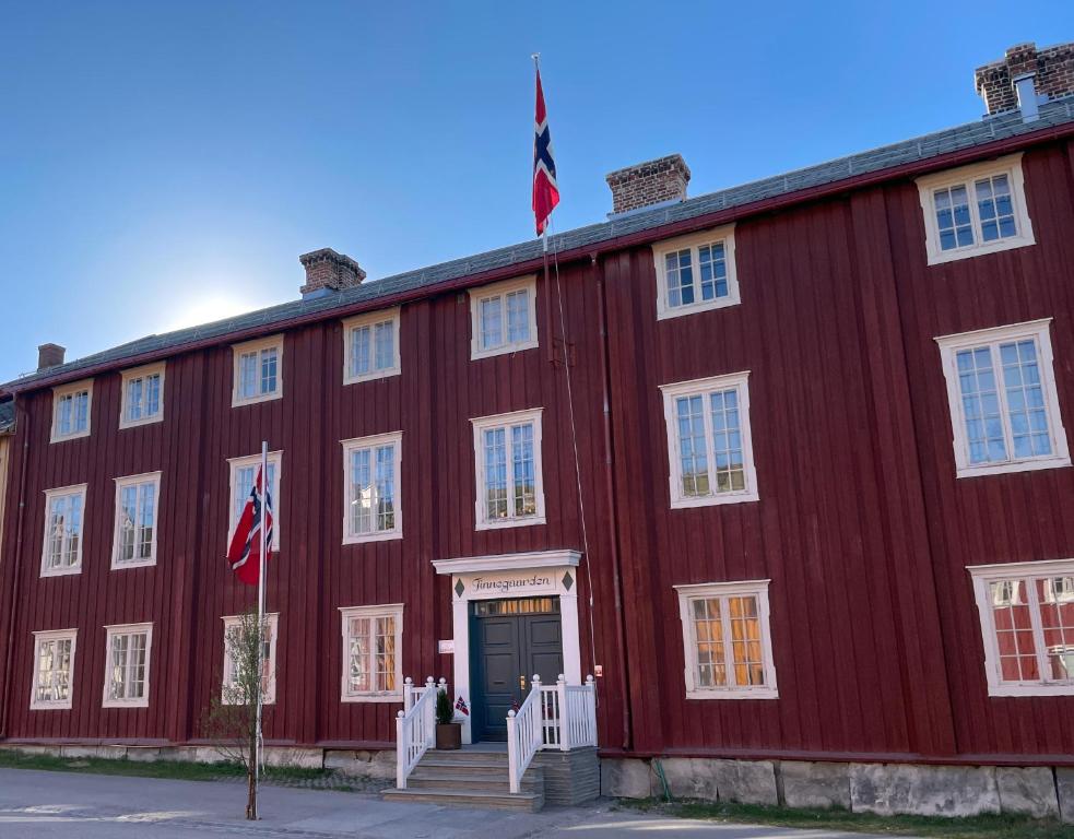 勒罗斯Finnegården Røros的前面有两面旗帜的红色建筑
