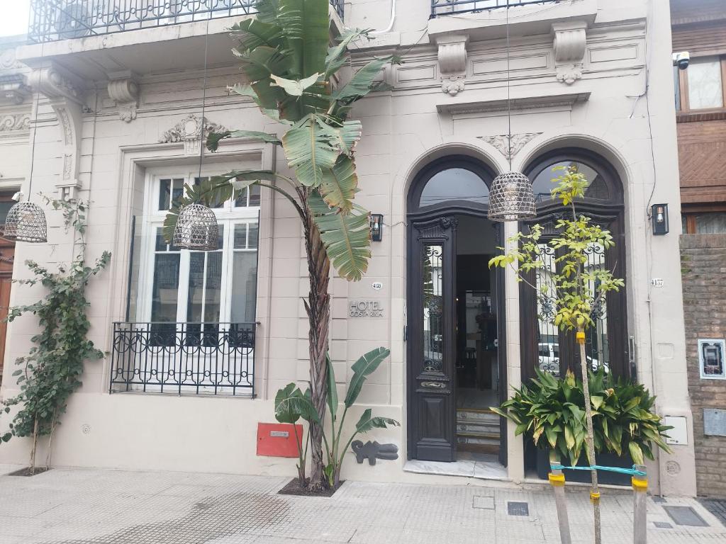布宜诺斯艾利斯哥斯达黎加酒店的白色的建筑,有黑色的门和一棵树
