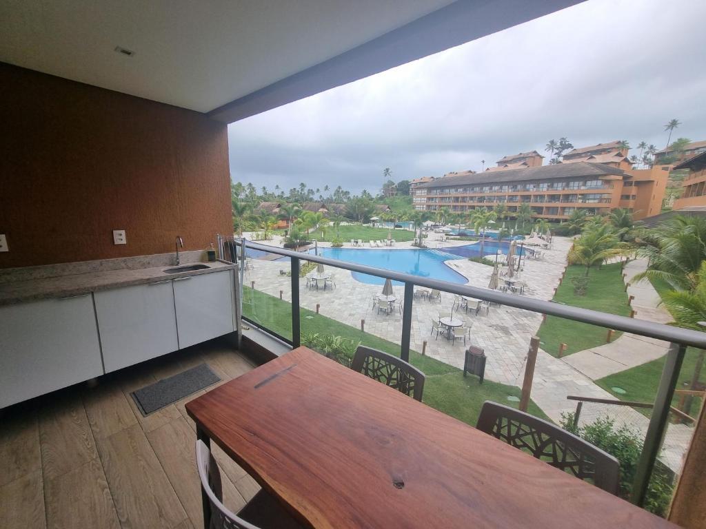 塔曼达雷Flat Eco Resort-Praia dos Carneiros的阳台配有桌子,享有游泳池的景色