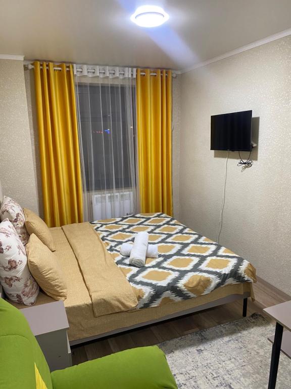 比什凯克Нарэл的一间卧室配有一张黄色窗帘和一台电视。