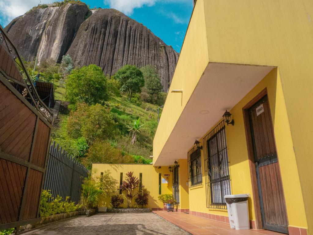 瓜塔佩Hermosa casa de campo en GUATAPÉ的一座黄色的建筑,背景是一座山