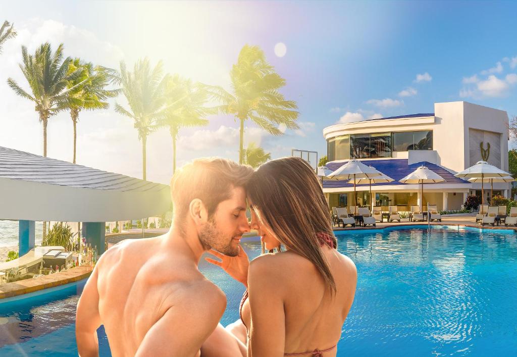 莫雷洛斯港Desire Riviera Maya Pearl Resort All Inclusive - Couples Only的坐在游泳池旁的男人和女人