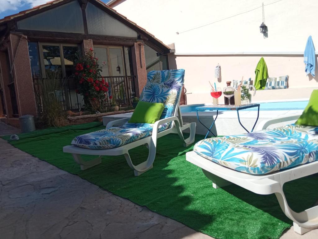 昆卡casa rural El Burrillo的两把椅子坐在泳池旁的绿色地毯上
