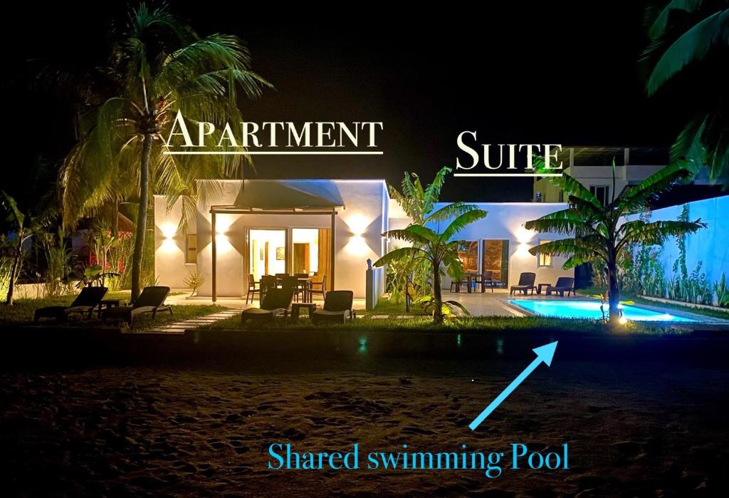 BunjuLions Zanzibar SUITE&APARTEMENT with private pool - LUXURY ON THE SEASIDE的享有度假村的夜景,设有阅读迷人的冲浪共用游泳池的标志