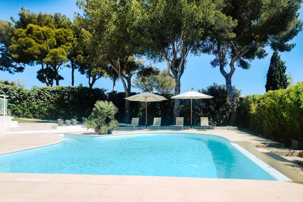 雷以桑布尔LA VILLA ALBA的一个带遮阳伞和椅子及树木的游泳池