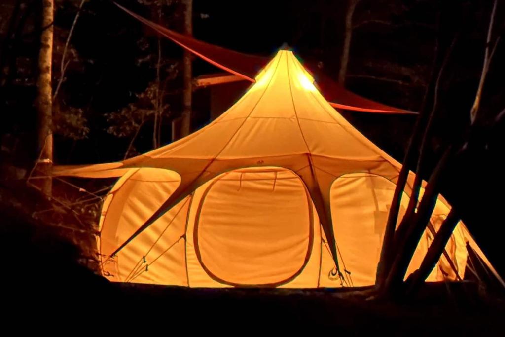 科斯比Mimosa Hill Wanderlust Woods的大型帐篷在晚上点燃