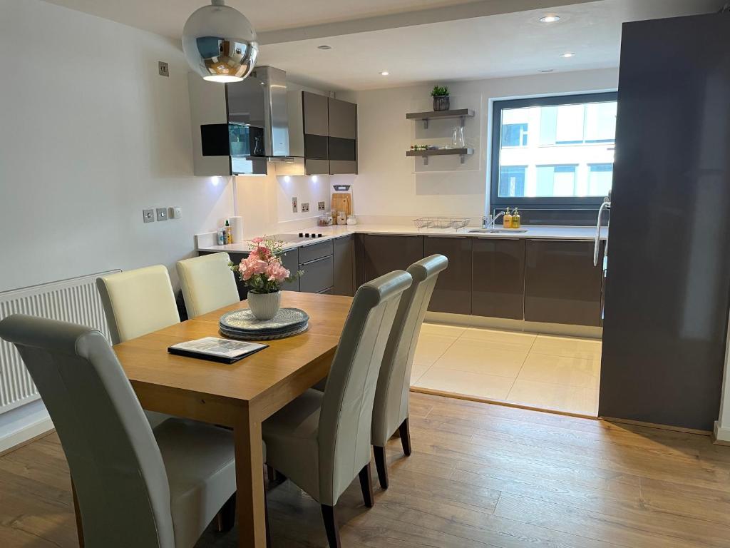 吉尔福德2 Bed, 2 Bath Apartment in Guildford Town Centre的厨房以及带木桌和椅子的用餐室。