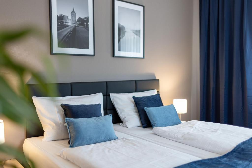 曼海姆魏格纳酒店的一间卧室配有两张带蓝白色枕头的床