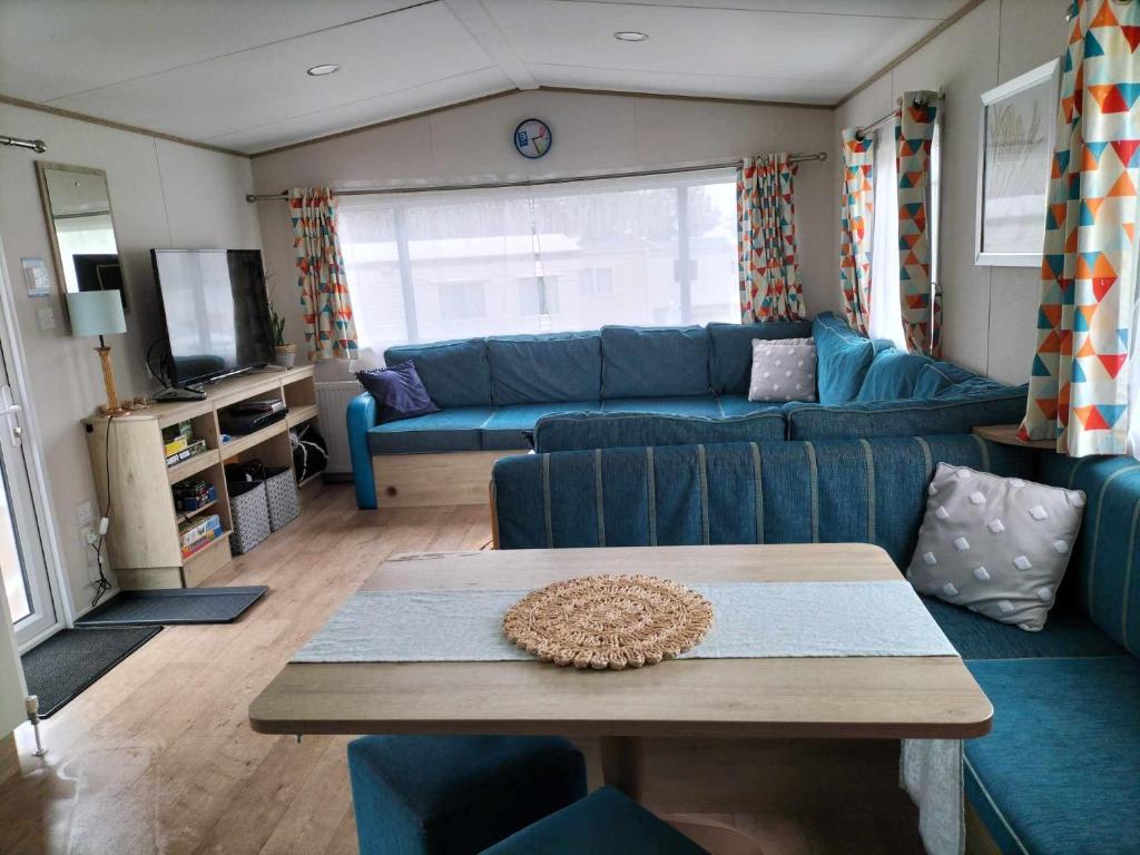 塞顿港Abi static caravan close to Edinburgh的客厅配有蓝色的沙发和桌子