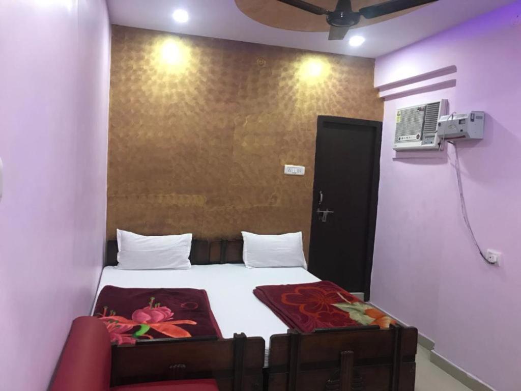 坎普尔Goroomgo Atithi Galaxy Kanpur Near Railway Station - Hotel-at-Prime-Location Spacious-Room with-wi-fi & Parking Availability,的一间卧室配有一张带红色椅子的床和一扇门