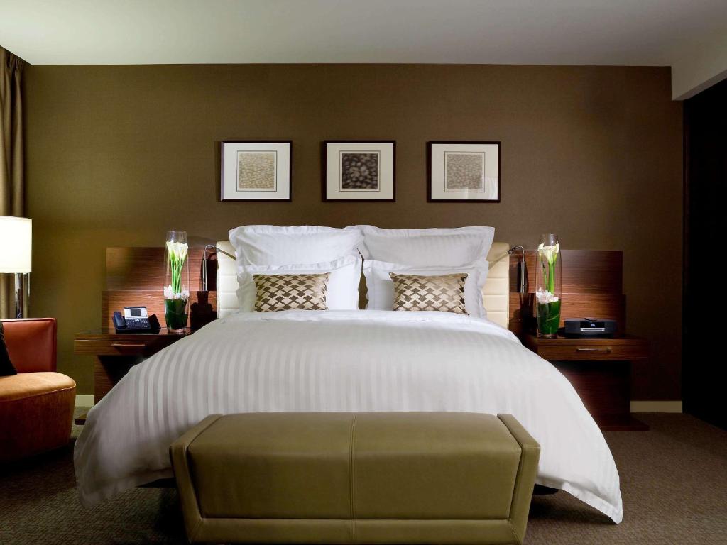 悉尼铂尔曼悉尼奥林匹克公园酒店的卧室配有一张白色大床和一把椅子