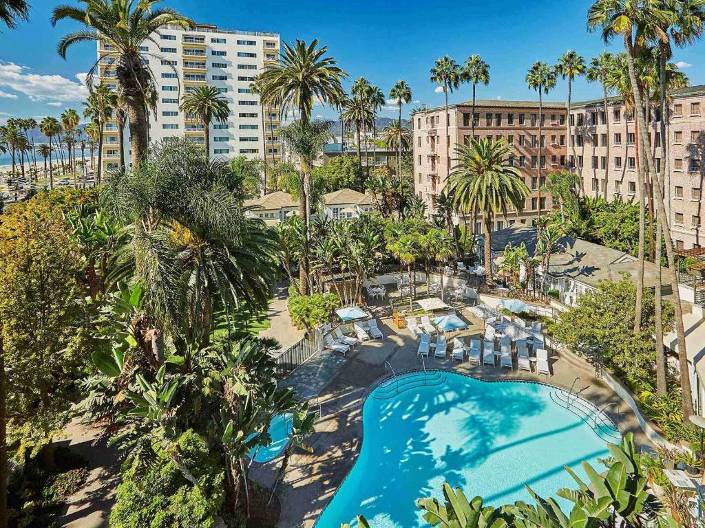 洛杉矶费尔蒙米拉马尔酒店&单层小屋的享有棕榈树和建筑的游泳池的顶部景致