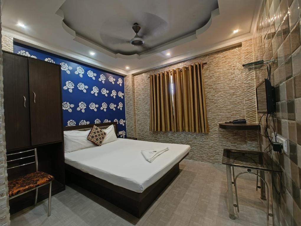 加尔各答金色天堂酒店的一间卧室设有一张床和蓝色的墙壁