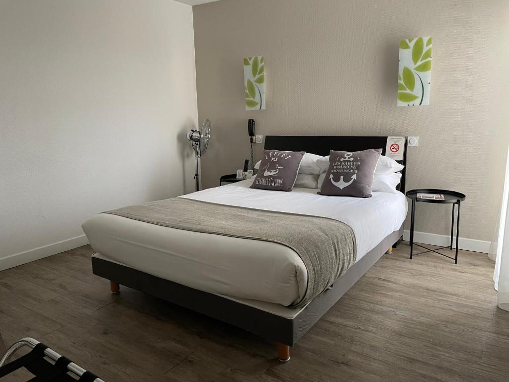 莱萨布勒-多洛讷Cit'Hotel Le Chêne Vert的一间卧室配有一张大床和两个枕头