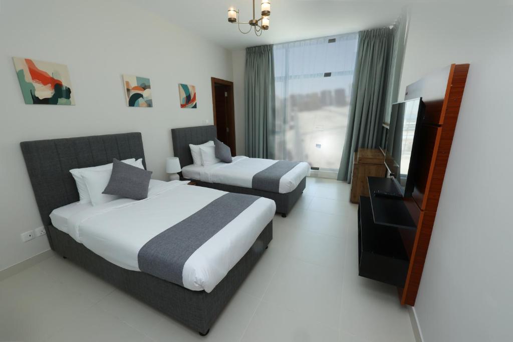 麦纳麦Noor Amwaj Hotel & Apartment的酒店客房设有两张床和一台平面电视。
