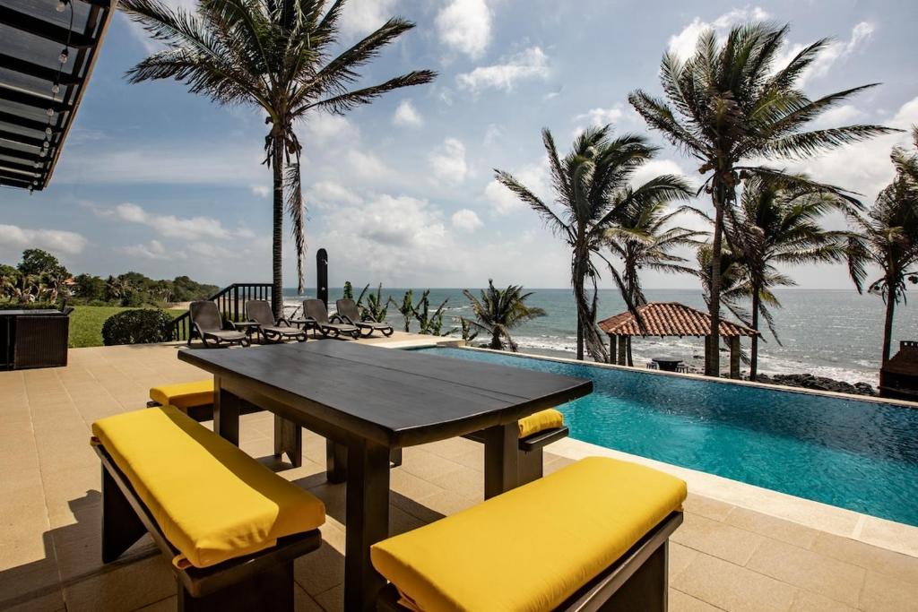 佩达西镇Super Private Beachfront 3BR Villa with Infinity Pool Andromeda Pedasi的游泳池旁带桌椅的天井