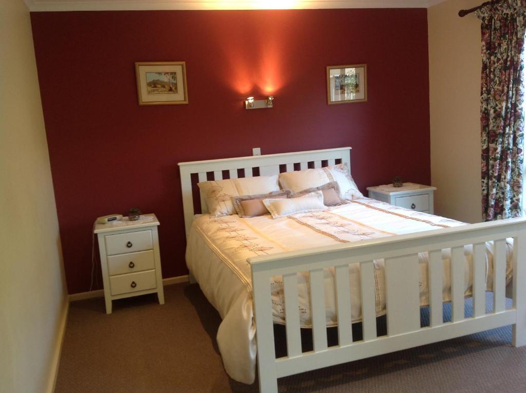Encounter Bay布里克维农家乐的卧室配有白色婴儿床和红色墙壁