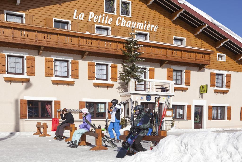 热克斯Logis Hôtel La Petite Chaumière的一群人坐在大楼前的滑雪板上