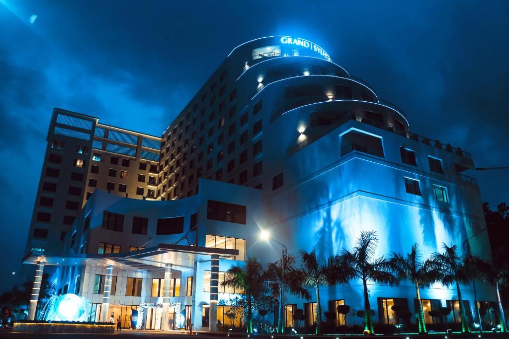 巴纳内拉斯Grand Sylhet Hotel & Resort的一家晚上有蓝色建筑的酒店