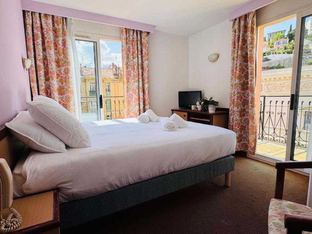 芒通奈艾夫的酒店的一间卧室设有一张大床和一个窗户。