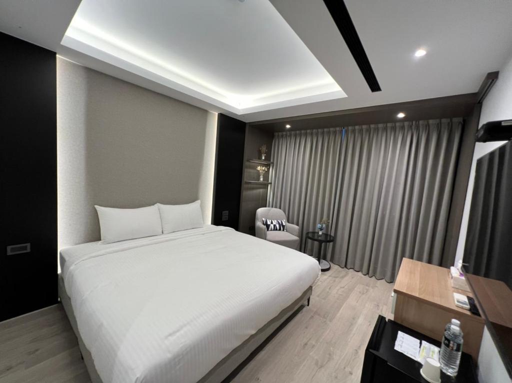 台中市侎雅行旅 台中捷運站館 Mya INN的卧室配有一张白色大床和一张书桌