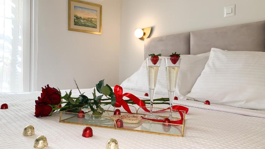 阿尔戈斯托利翁Rouchotas Apartments的一张带两杯香槟酒和玫瑰的床