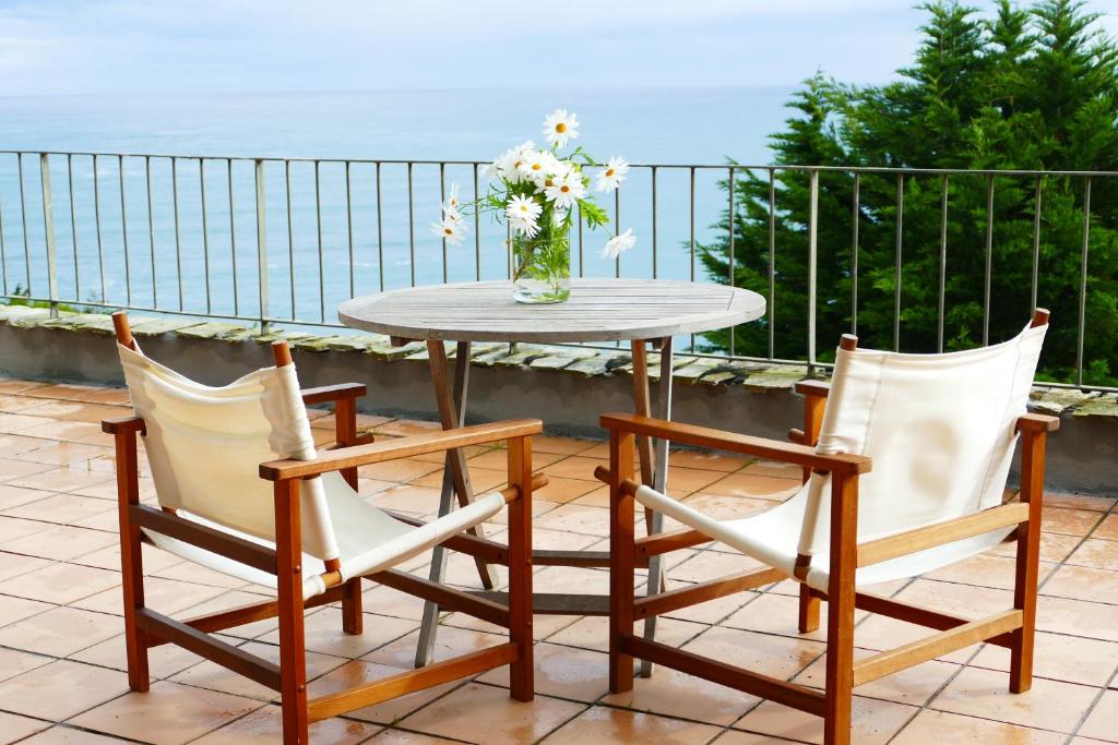 柯米拉斯Apartamento en Comillas_Rovacias guest house的一张桌子和两把椅子,花瓶
