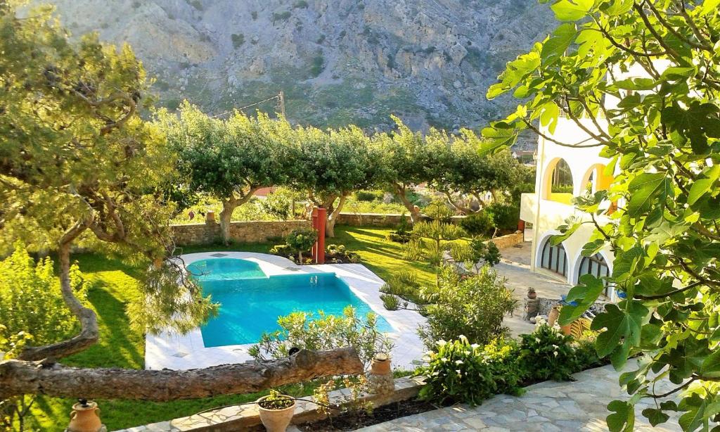KeramesPetrinos Milos的一座花园内的游泳池,花园内种有树木,建筑中