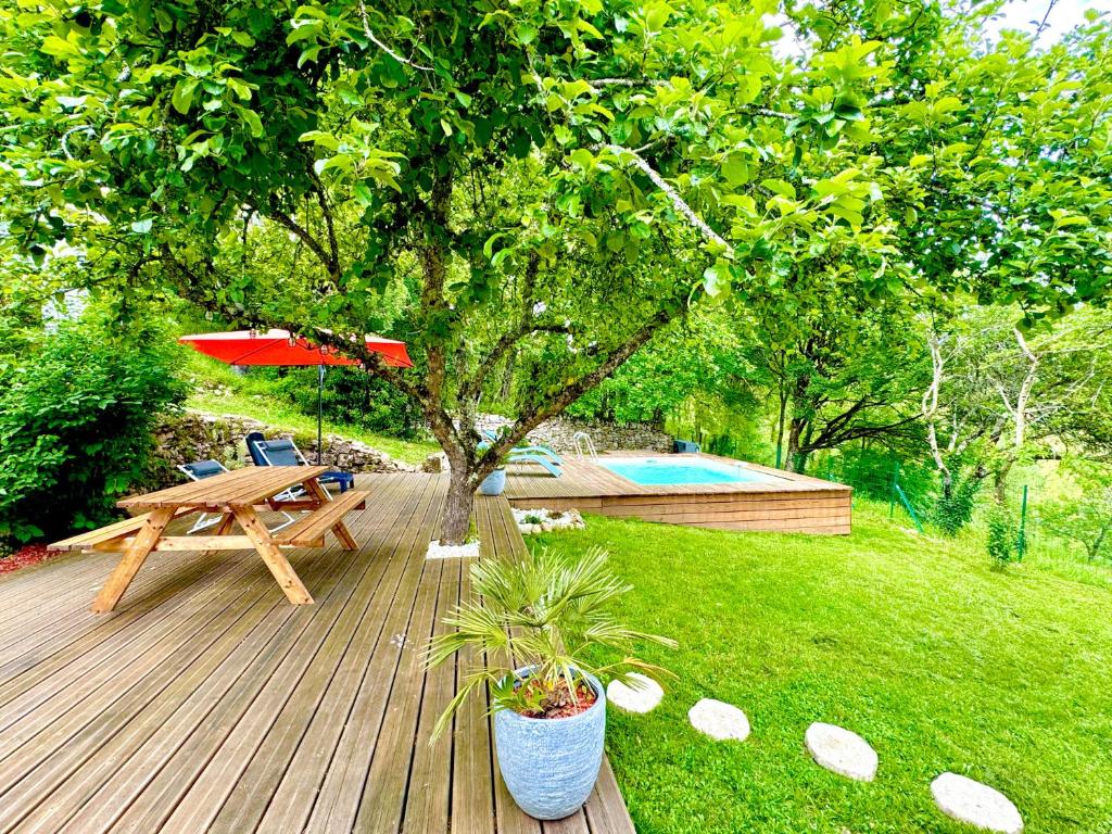 鲁埃格自由城La Combe aux oiseaux的木甲板上配有野餐桌和遮阳伞