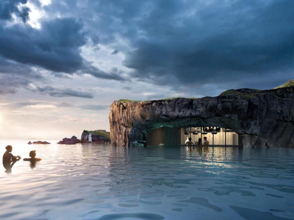 雷克雅未克Ocean View Suite near Sky Lagoon的一群人站在水面上,站在一个洞穴前