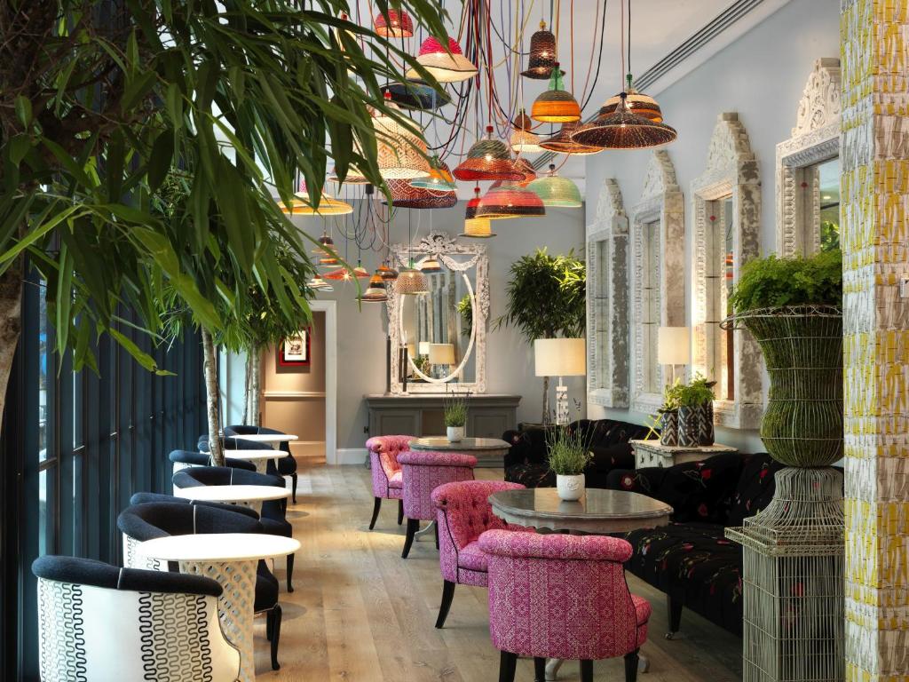 伦敦菲尔姆戴尔酒店集团汉姆庭院酒店的一间设有粉红色椅子和桌子的餐厅,种植了植物