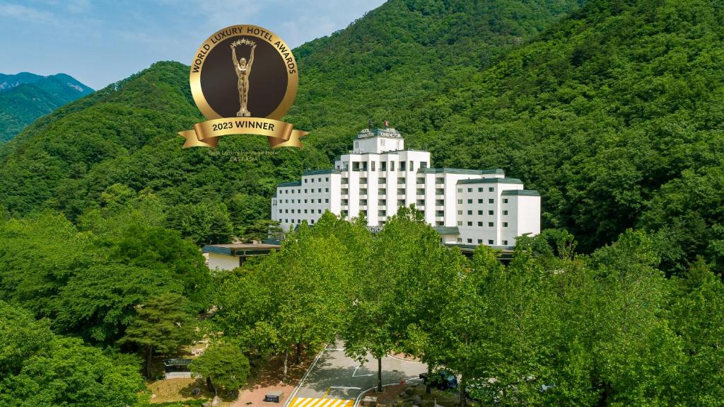 束草市KensingtonHotel Seorak的一座大型白色建筑,带有大标志,大山